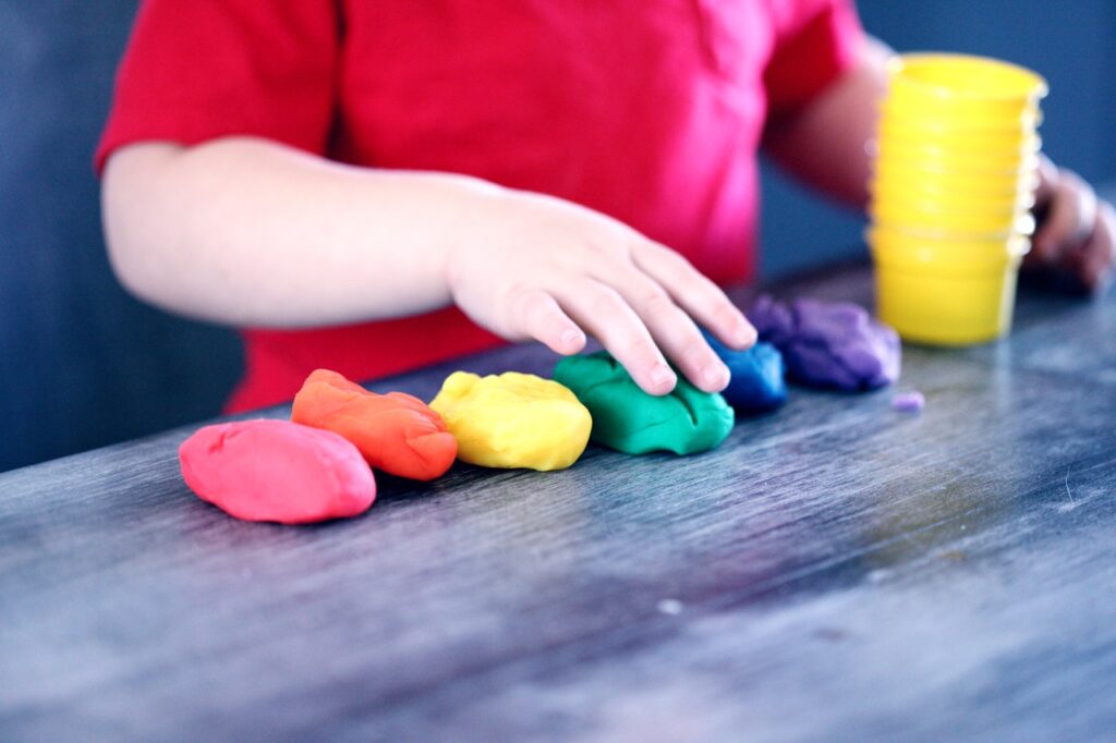 Imagen en la que aparecen las manos de un niño jugando con plastilina